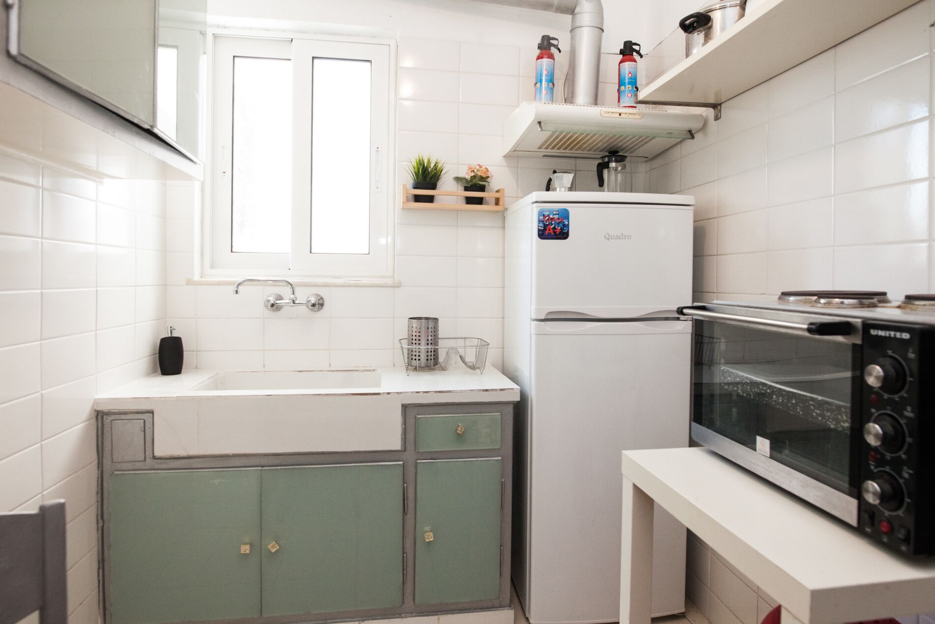 A compact kitchen with a refrigerator, microwave, and a window above the sink.
