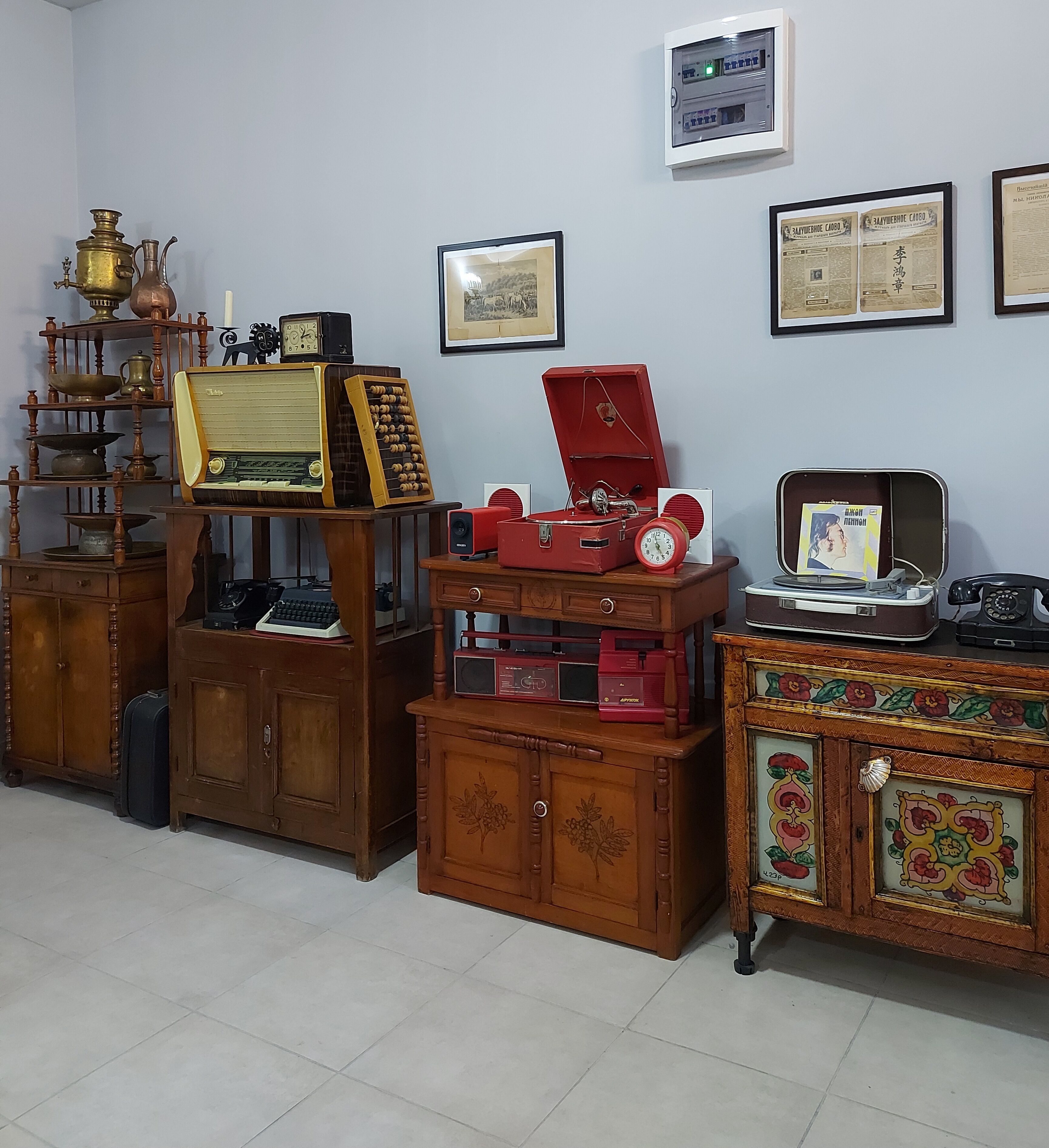 Une pièce meublée de meubles anciens en bois, comprenant une radio, une horloge et un meuble orné de carreaux décoratifs.
