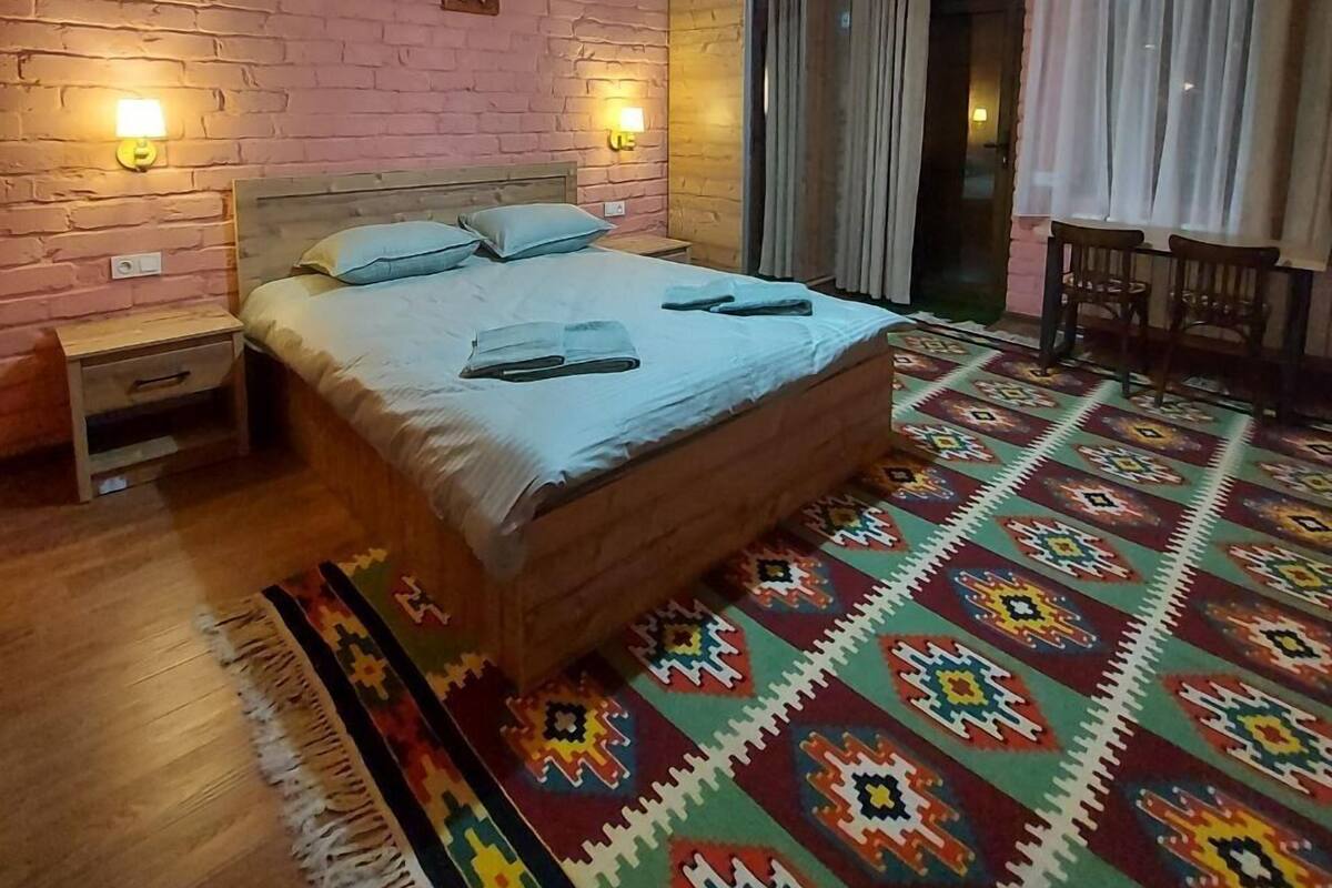 Une chambre à coucher avec un lit en bois, un tapis à motifs et deux lampes fixées au mur.