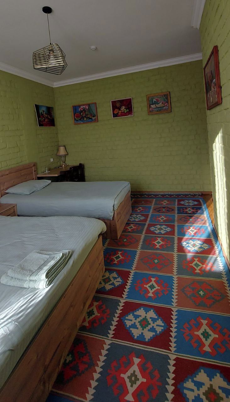 Una habitación con dos camas, un suelo estampado y cuatro cuadros colgados en la pared.