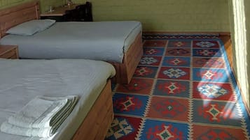 Una habitación con dos camas, un suelo estampado y cuatro cuadros colgados en la pared.