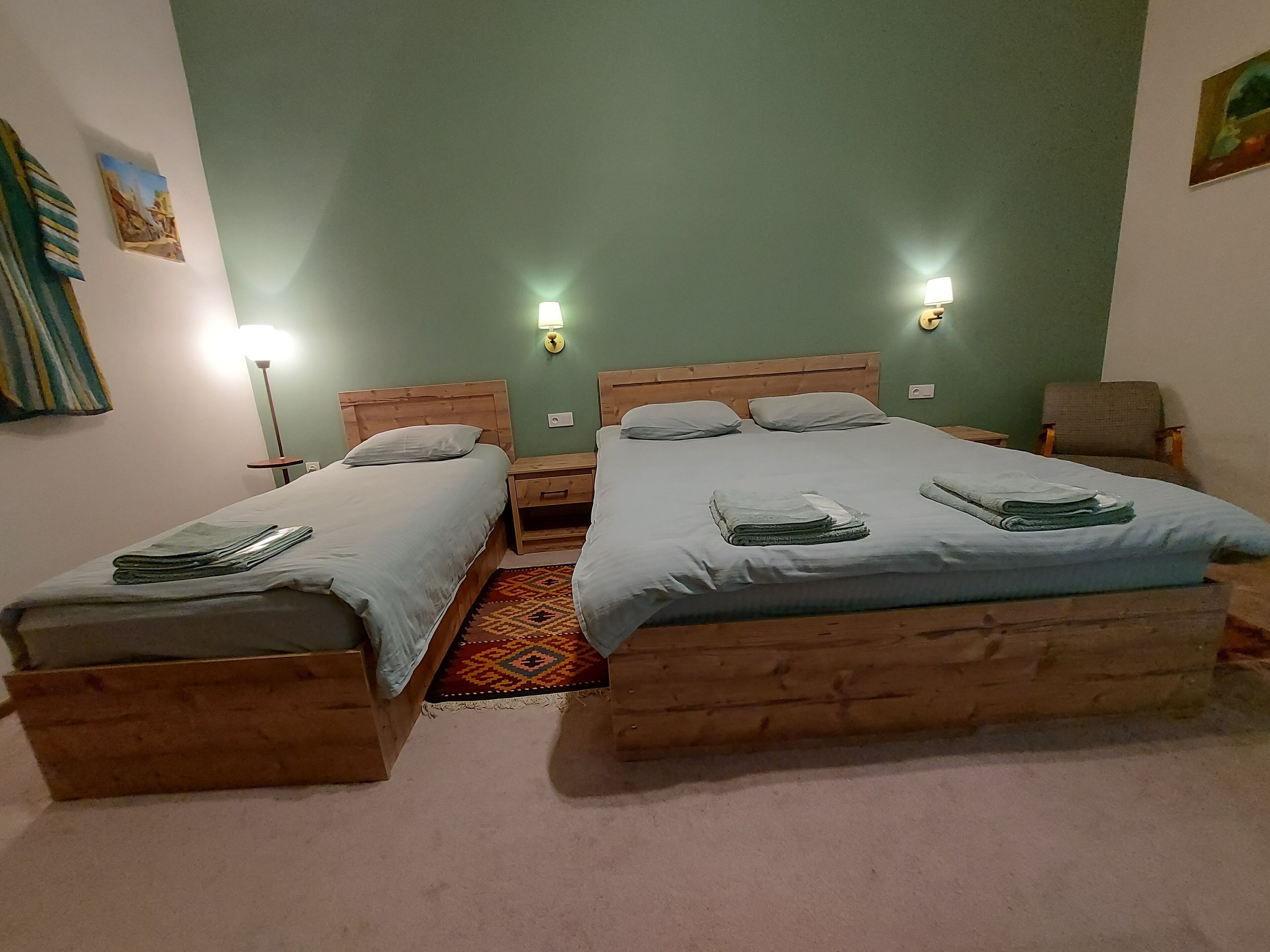 A room with two wooden beds, each with a nightstand, a lamp, and a chair.