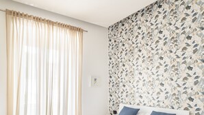 Ein modernes Schlafzimmer mit einem großen Bett, einem Nachttisch und einer Wand mit einem Blumenmuster.