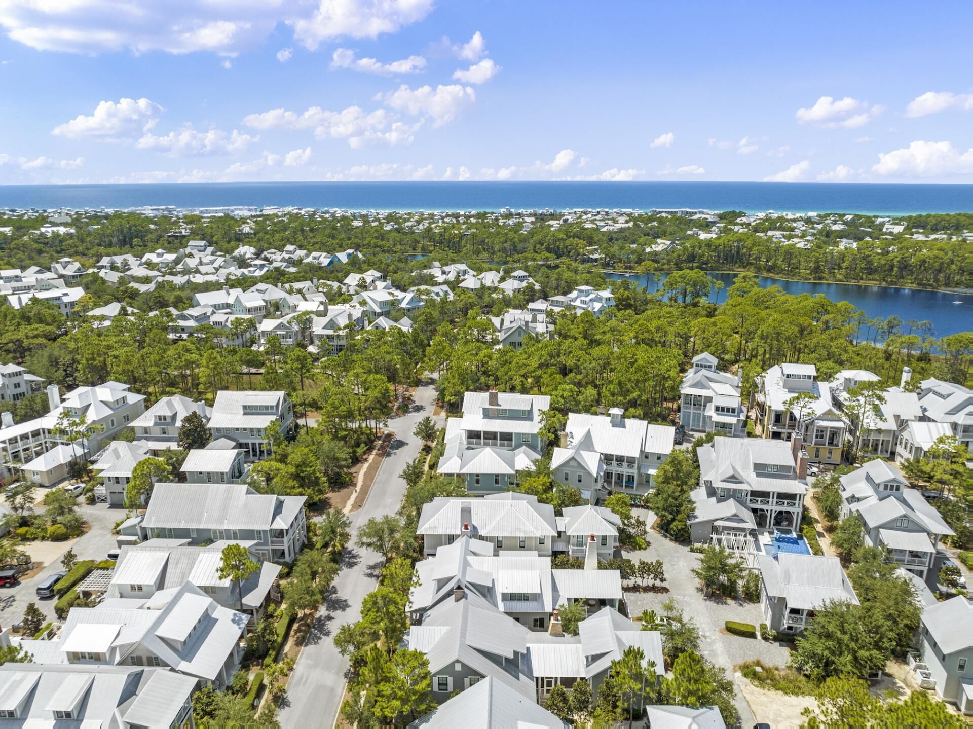 An aerial view of a coastal residential area with houses, roads, and a body of water.