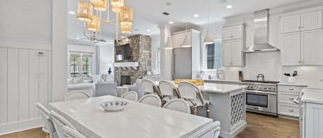 A modern kitchen with white cabinetry, a large island with seating, a stone accent wall, and a built-in stove.