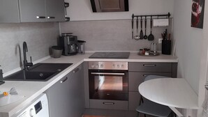 Une cuisine compacte équipée d’un lave-linge, d’un évier, d’une cuisinière et d’un petit coin repas avec une table et des chaises.