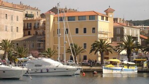 Ein Yachthafen mit vor Anker liegenden Booten, ein Gebäude mit der Aufschrift 'PROPIA' und Palmen.
