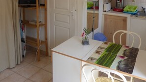 Eine kleine Küche mit weißem Tisch, Stühlen und einem Schrank.