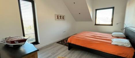 A bedroom with a bed, a wooden dresser, a fur rug, and a window.