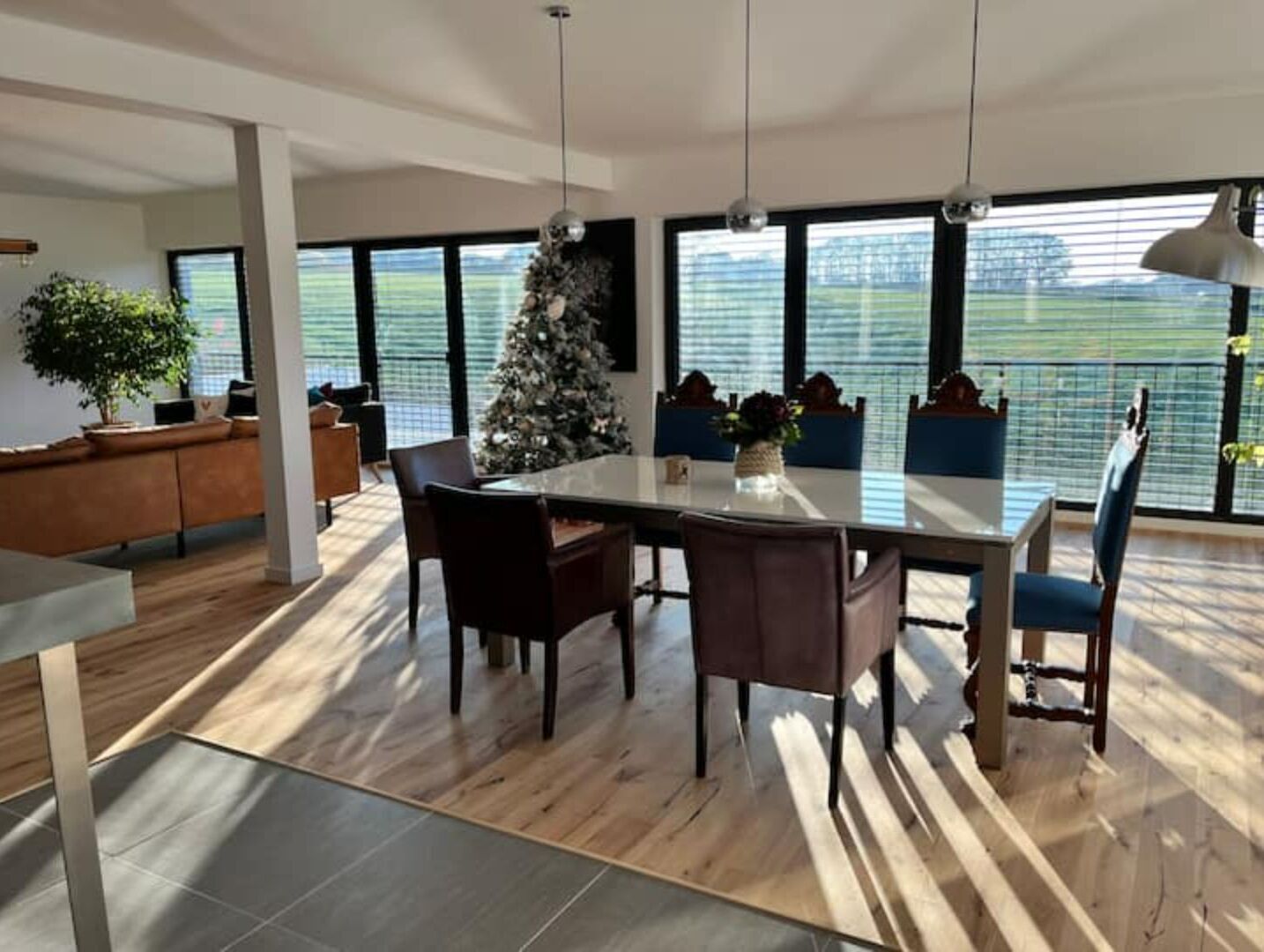 Un comedor moderno con una mesa grande, sillas y un árbol de Navidad.