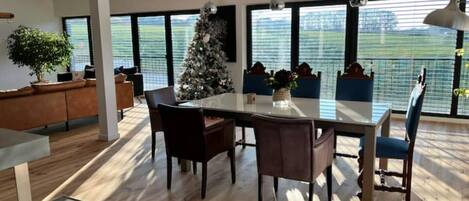 Un comedor moderno con una mesa grande, sillas y un árbol de Navidad.
