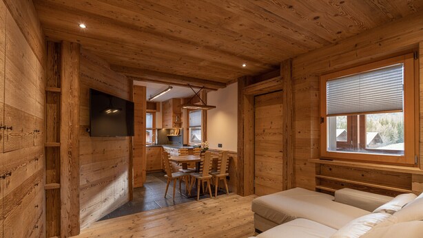 A cozy cabin interior with wooden walls, a dining area, and a sofa. - Casa Ca Dei Pini, surrounded by Nature (Cortina d´Ampezzo)