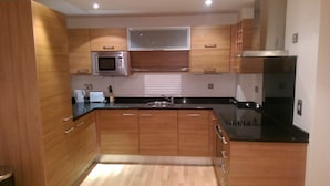 A modern kitchen with wooden cabinets, a microwave, a stove, and a black countertop. - Ch & bro properties Ltd (Leeds)