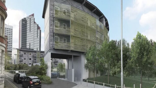 A modern building with a curved roof and a flat facade, surrounded by greenery and other buildings. - Ch & bro properties Ltd (Leeds)