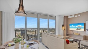 Ett modernt hotellrum med en balkong, en matplats, en soffa och en TV.