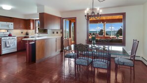 Una cocina moderna con armarios de madera, una estufa de acero inoxidable y un comedor con mesa de vidrio y sillas de metal.