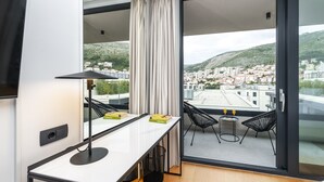 A modern room with a large window, a dining table with chairs, and a view of a cityscape. - City Residences (Dubrovnik)