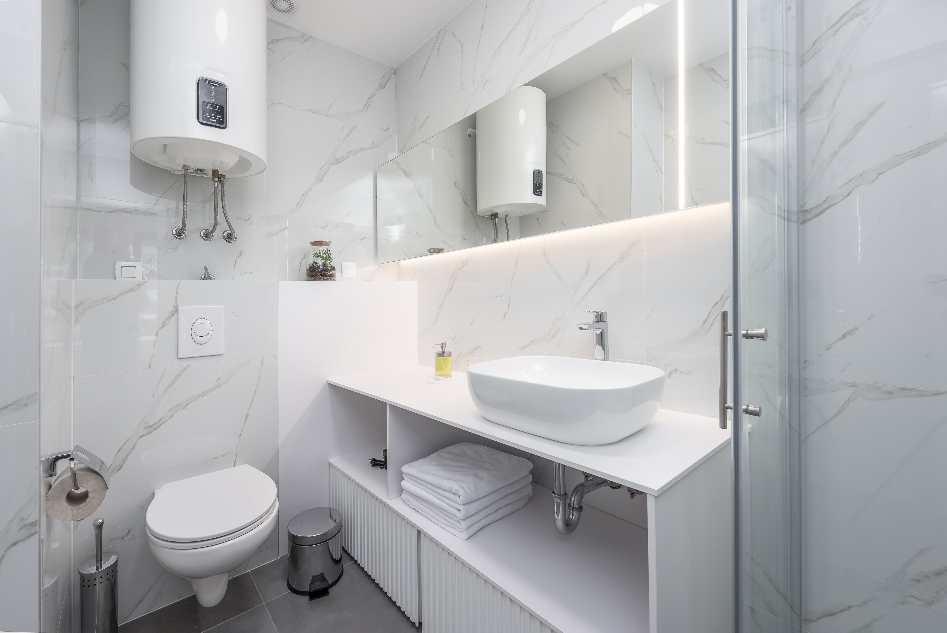 Une salle de bain moderne avec un lavabo, des toilettes et une douche, le tout de couleur blanche.