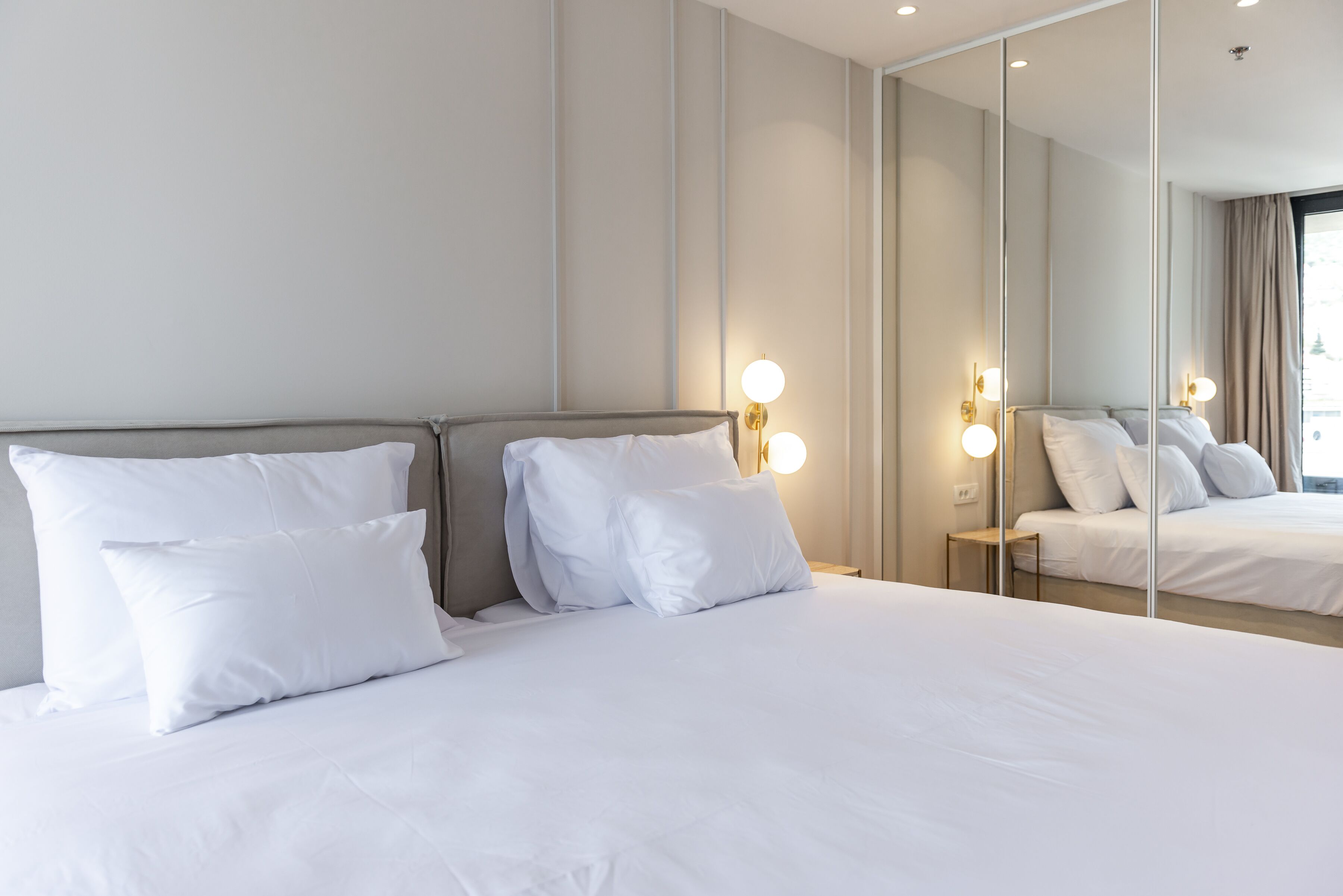 Une chambre d’hôtel avec un grand lit, deux tables de chevet et un miroir.