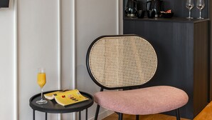 A modern room with a black chair, a small round table with a glass of orange juice, and a black shelf with a coffee maker and glasses. - City Residences (Dubrovnik)