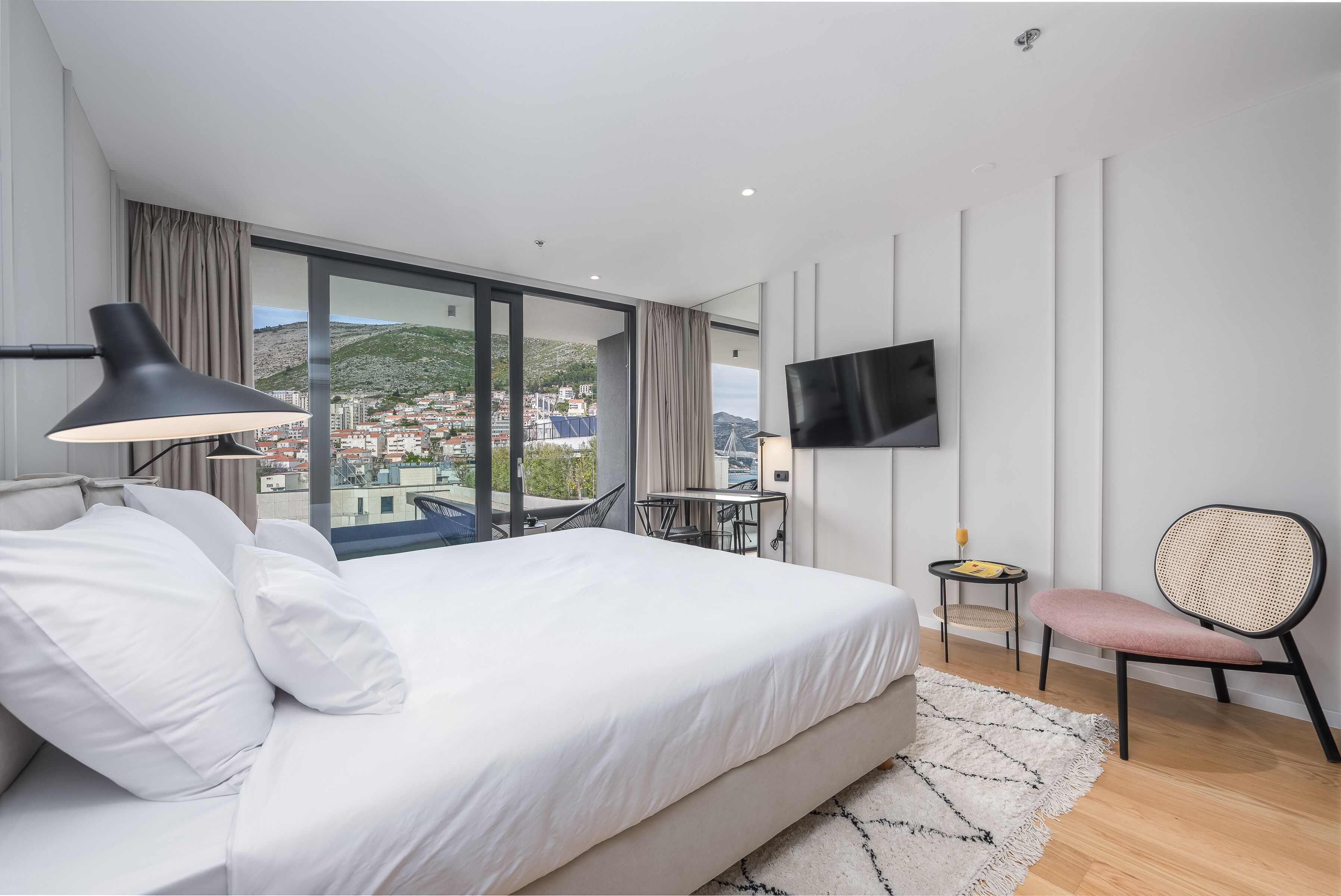 Une chambre d’hôtel moderne dotée d’un grand lit, d’un bureau, d’une chaise, d’une télévision et offrant une vue sur le paysage urbain.