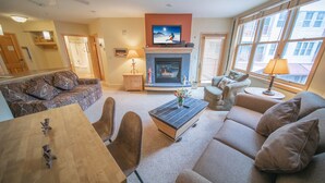A living room with a fireplace, sofa, coffee table, and a television mounted above the fireplace. - Walk to River Run, dining, shopping, Hot tubs (Keystone)