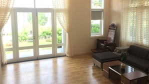 Un salon spacieux comprenant un canapé, une table basse et un fauteuil. De grandes portes vitrées donnent sur un jardin.
