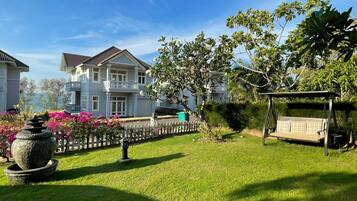 A well-maintained garden with a stone fountain, a swing, and a white picket fence.
