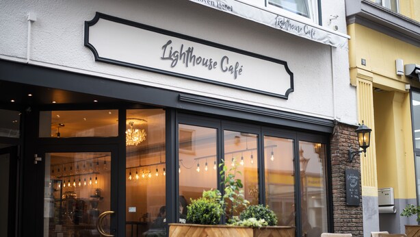 The exterior of Lighthouse Café with a wooden planter and seating area in front. - Bob W Bonn Zentrum (Bonn)