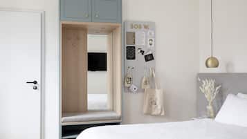 A bedroom with a bed, a wardrobe, a mirror, a bulletin board, and a hanging light fixture.