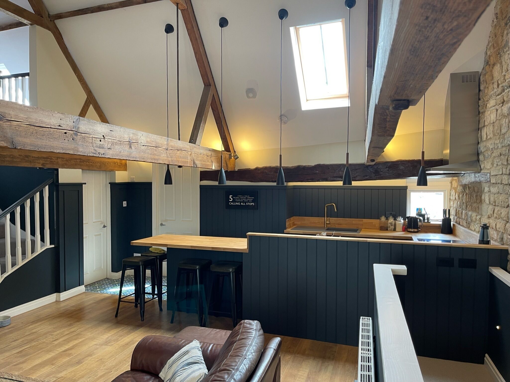 Una cocina moderna con una isla central, vigas de madera e iluminación colgante.