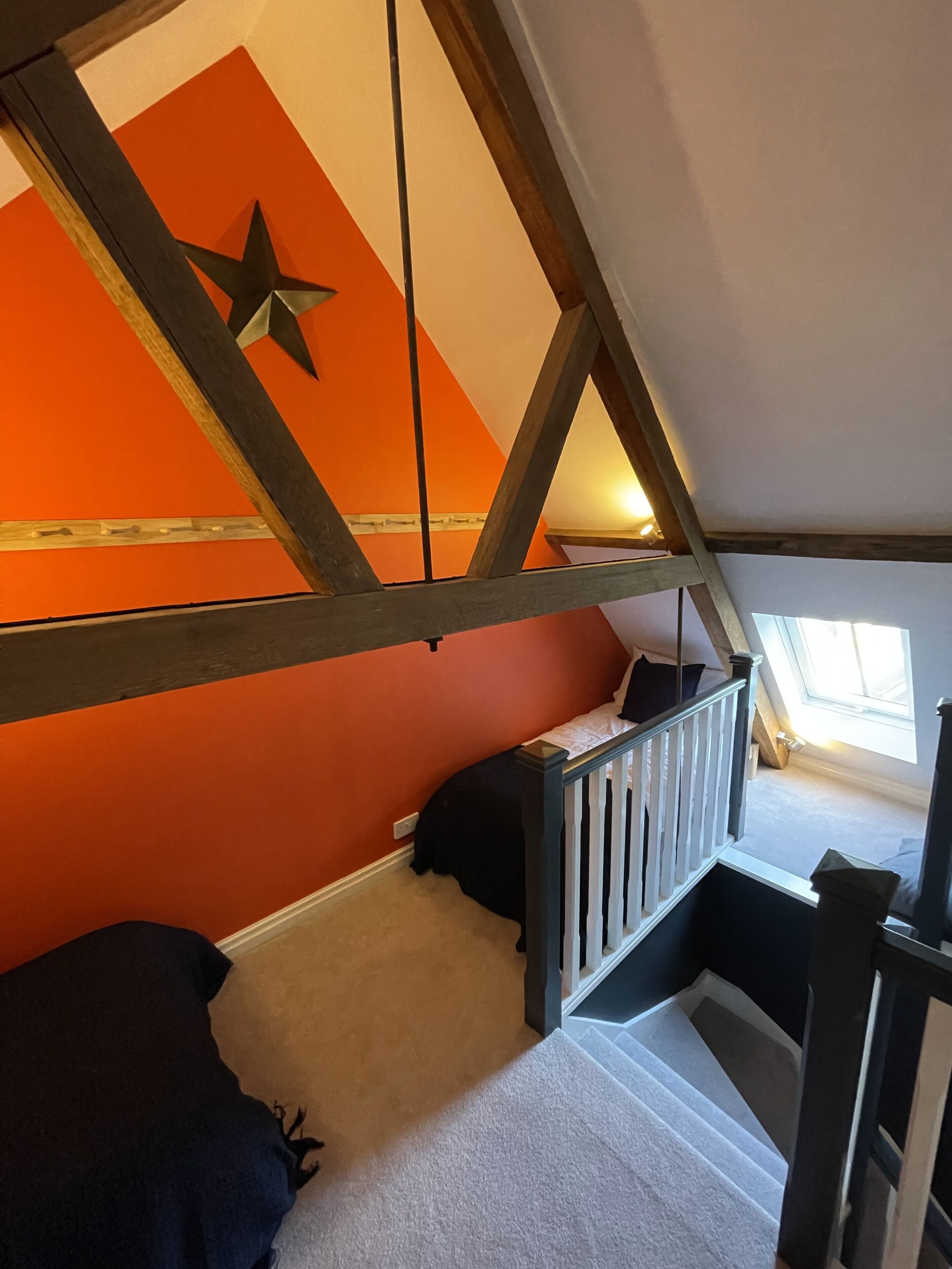 A loft bedroom with a sloped ceiling, a star decoration, and a window providing natural light.