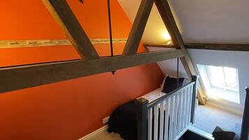 A loft bedroom with a sloped ceiling, a star decoration, and a window providing natural light.