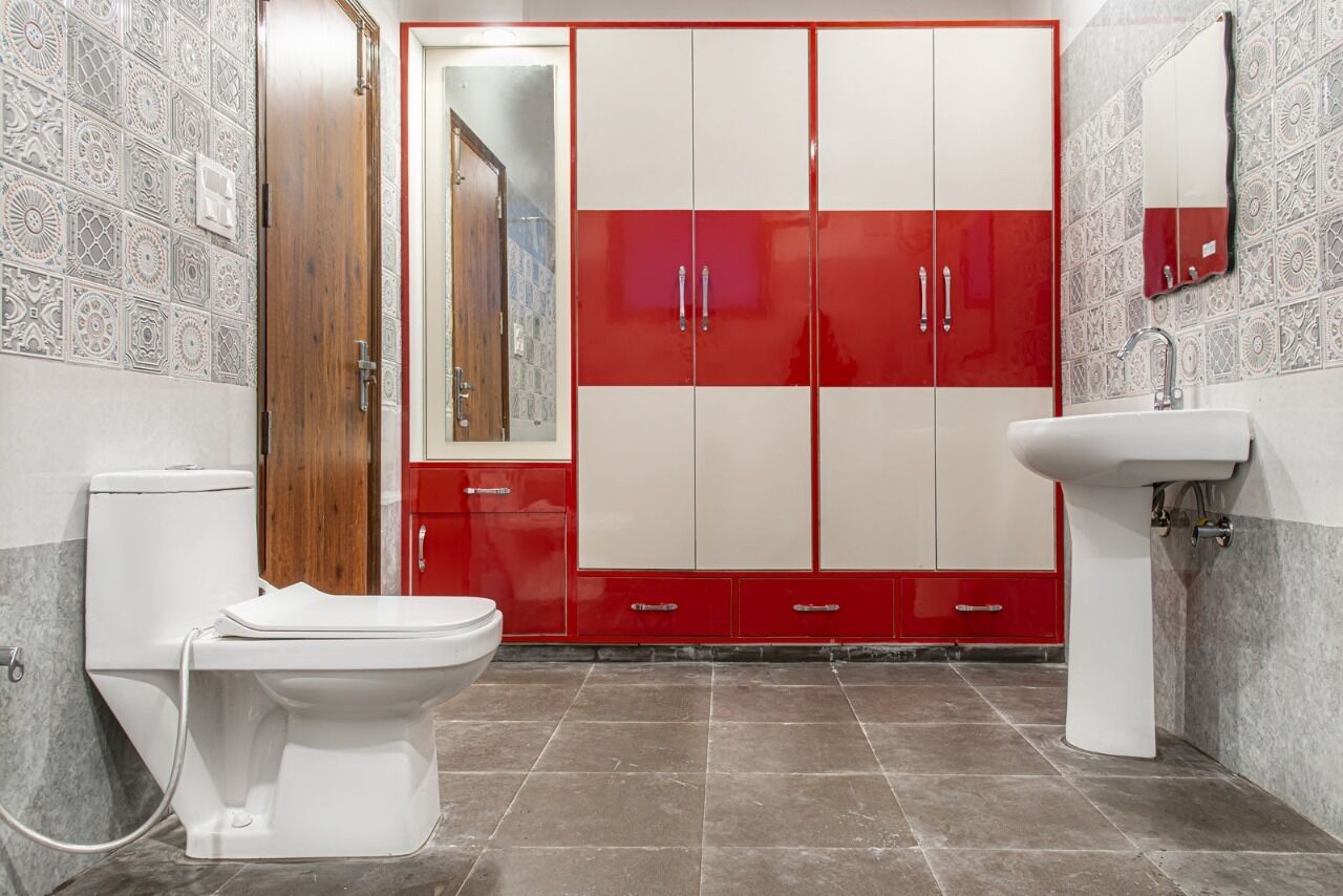 A bathroom with a toilet, sink, and red and white cabinets.