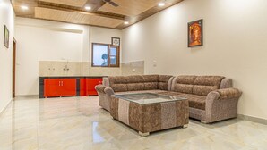 A spacious living area with a sectional sofa, a glass coffee table, and a red cabinet. - The Bryll Homes (Krishangarh)
