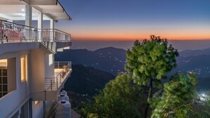 A hotel with a balcony overlooking a mountainous landscape at sunset. - The Bryll Homes (Krishangarh)