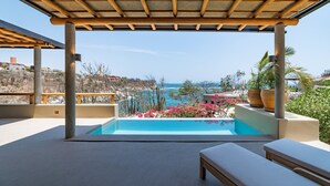 Un espace piscine avec vue sur la mer, agrémenté de plantes en pot et d’une pergola.