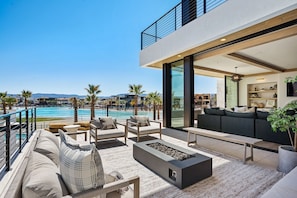 A modern outdoor living area with a pool, seating, and a view of the pool and mountains.