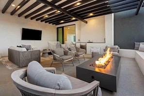 A modern living room with a fireplace, comfortable seating, and a kitchen area.