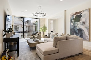 A modern living room with a sofa, coffee table, and a large abstract painting.