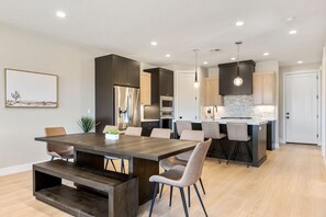 Una cocina moderna con una isla central, electrodomésticos integrados e iluminación colgante.
