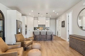 A modern kitchen with white cabinets, a stainless steel refrigerator, and a central island with bar stools.