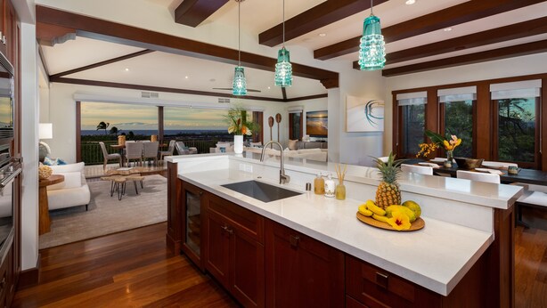 A spacious kitchen with a large island, wooden cabinets, and a view of the outdoors.