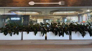 Ein modernes Café-Interieur mit einer Holzwand, die den Schriftzug 'CAFE 410' und ein löffelähnliches Designelement zeigt.