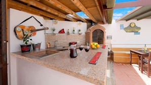 Una cocina con encimera de granito, una guitarra y un reloj en la pared.