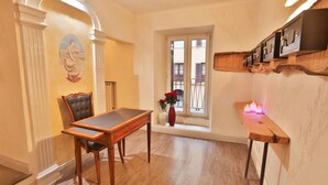A dining area with a wooden table and chairs, a vase with flowers, and a window with a view of balconies. - Grottini Luxury Suites - Pantheon (Rome)