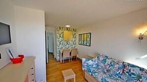 A bedroom with a bed, a desk, a chair, and a small table. There is a mirror on the wall and a window with a view. - Apartment Cap Esterel sea view with reversible air conditioning (Saint-Raphaël)