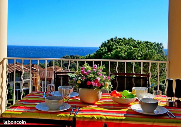A balcony with a table set for two, overlooking the sea.