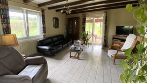 A living room with a black sofa, a wooden coffee table, a television, and a bookshelf.