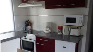 A compact kitchen with a microwave, toaster, and coffee maker on the countertop. - Maison Tout Confort à Lacanau Océan (Lacanau)